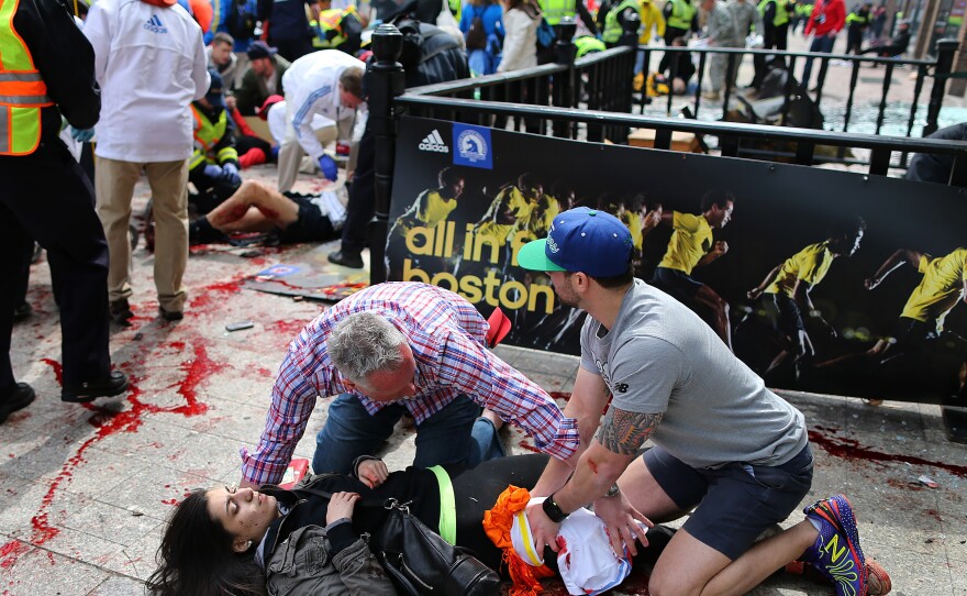 Bystanders help Sydney Corcoran at the scene of the first explosion near the finish line of the 117th Boston Marathon.