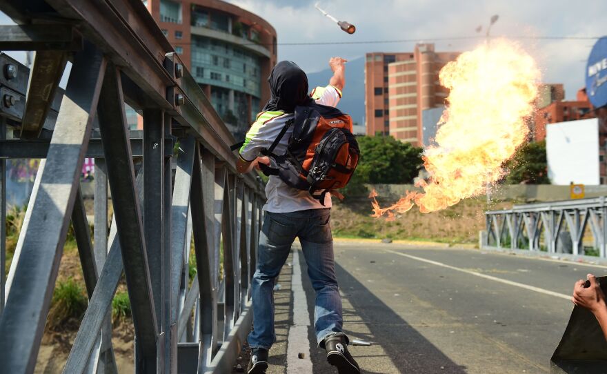 A protester tosses a combustible device during a clash with riot police in Caracas on Wednesday.