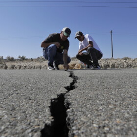 Ron Mikulaco, left, and his nephew, Brad Fernandez, examine a crack caused by an earthquake on highway 178 Saturday, July 6, 2019, outside of Ridgecrest, Calif. 