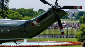 A May Day protest can been seen in front of the Jefferson Memorial with Marine One on the South Lawn of the White House before President Donald Trump departs, Friday, May 1, 2026, in Washington.