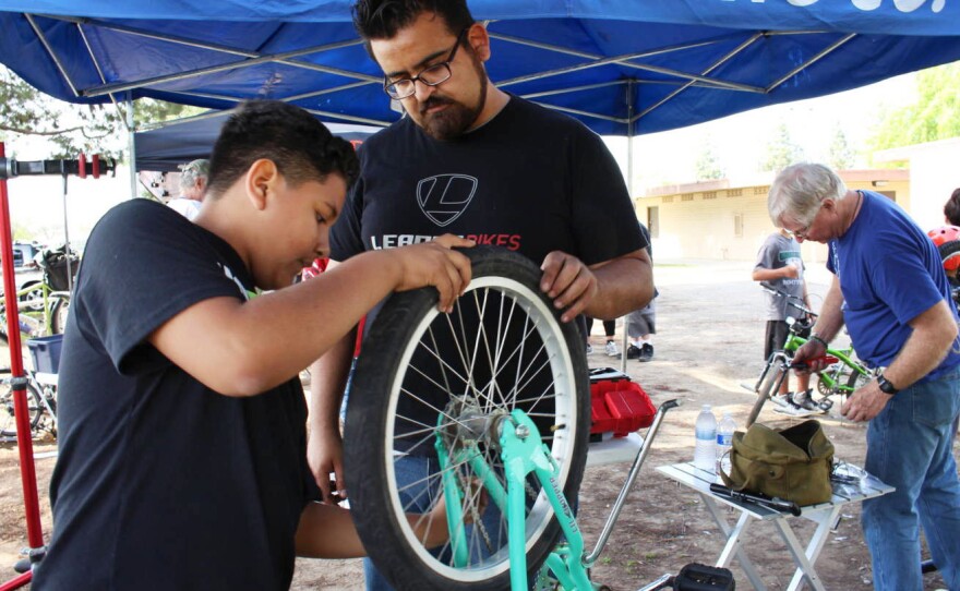 Jaime Rangel helps Gustavo Ruiz, 12, align a tire on his bike, at a recent community event in southeast Fresno, Calif. As manager for Bici Projects, Rangel promotes cycling in the Latino community as a great way to get in shape.