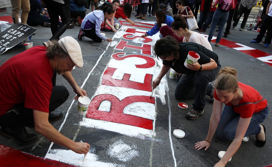 Protesters paint a mural on the street during a May Day demonstration outside of a U.S. Immigration and Customs Enforcement office in San Francisco, Calif.