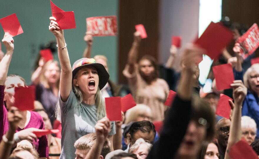 Constituents hold up red signs of disagreement with Sen. Lindsey Graham during a town hall meeting today in Columbia, S.C.