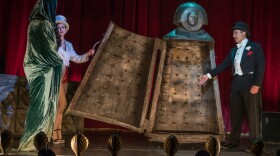 Old school magician, Lawrence Pross (Daniel Cerqueira on right), is in the midst of his grand finale when tragedy strikes and his unlucky volunteer is fatally trapped in his medieval iron maiden.