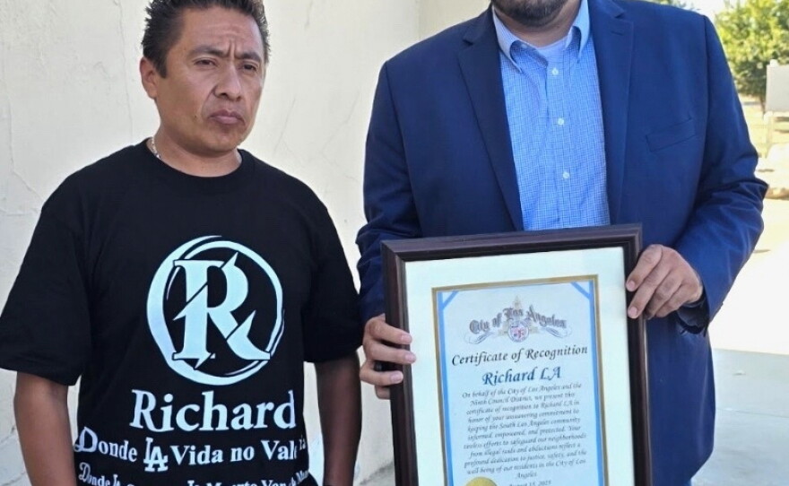 Carlitos Ricardo Parias (left) receives a certificate of recognition from Jose Ugarte, chief of staff for Los Angeles City Council member Curren Price, in Los Angeles in August 2025.