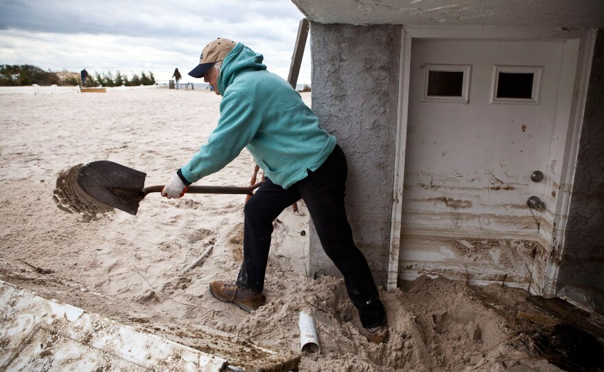 Barbara Young tosses sand out her front door in Long Beach, N.Y. The storm caused massive flooding across much of the Eastern Seaboard.