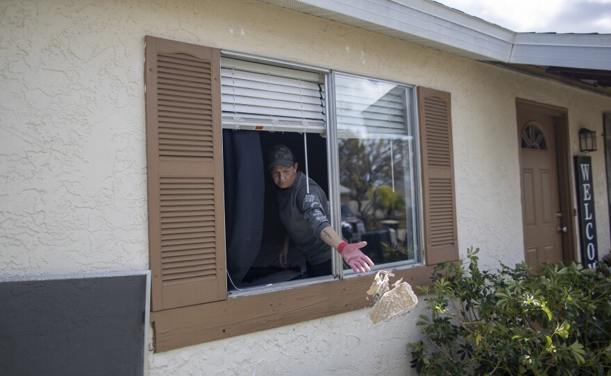 Tina Krasinski clears debris out of her mother's home in North Port, Fla., on Wednesday.
