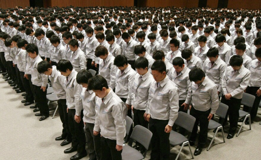 Newly recruited Toyota Motor employees bow their heads in prayer for disaster victims at a ceremony in Toyota City in Aichi prefecture on April 1.