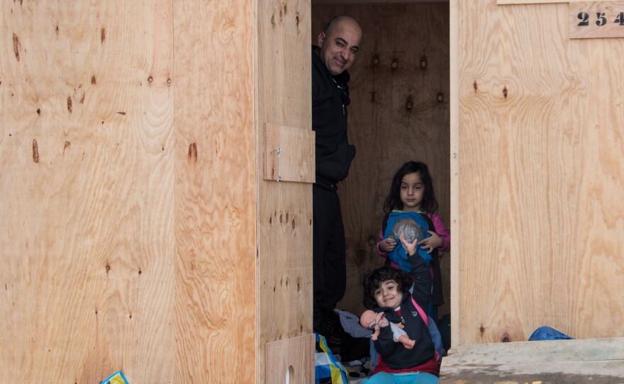 Iraqi Kurds look out from a wooden cabin on March 8, 2016, in Grande-Synthe, northern France, after coming from a nearby site where migrants and refugees have been living in miserable conditions.