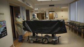 In this July 7, 2020, file photo, hospital staff members enter an elevator with the body of a COVID-19 victim on a gurney at St. Jude Medical Center in Fullerton, Calif. 