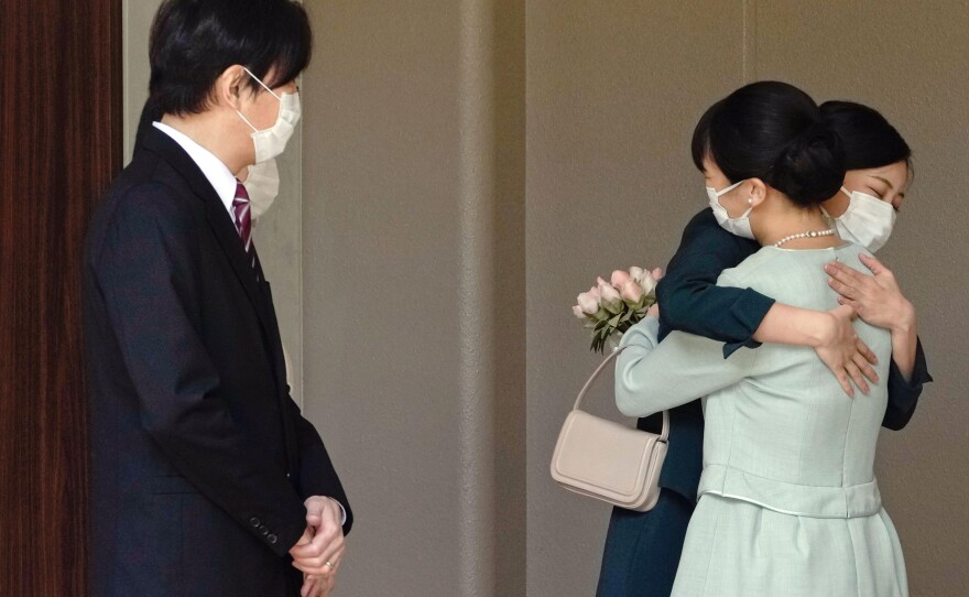 Japan's Princess Mako, right, hugs her sister Princess Kako, watched by her parents Crown Prince Akishino and Crown Princess Kiko, before leaving her home in Tokyo. Mako and  commoner Kei Komuro tied the knot Tuesday without wedding celebration in a marriage that has split public opinion over her would-be mother-in-law's financial controversy.