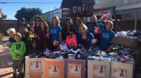 Home Start employees and program participants celebrate the donation of socks with SDCOE and California Coast Credit Union team members.