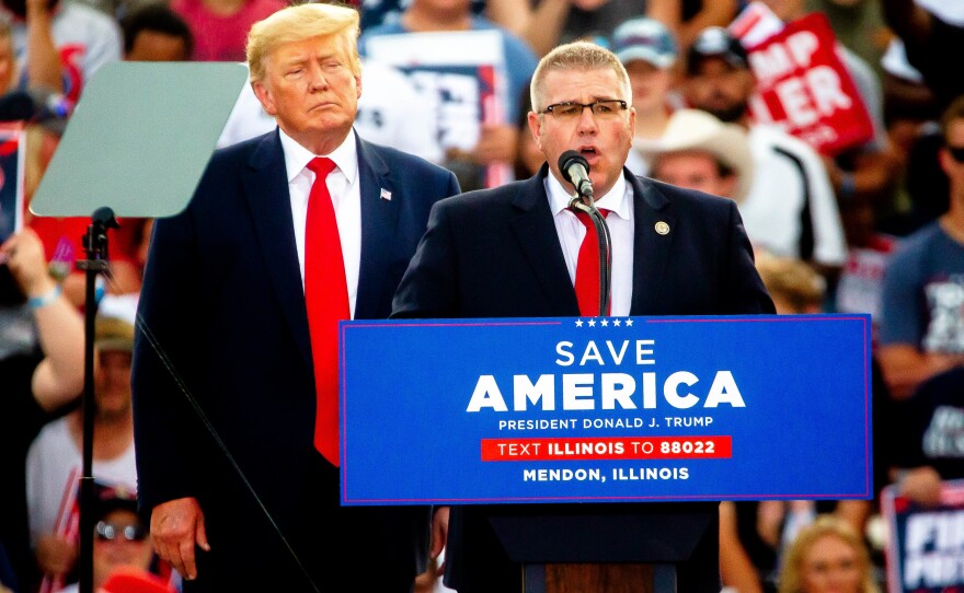 Darren Bailey, Illinois state Senator and Republican candidate for governor, speaks alongside former President Donald Trump on Saturday, June 25, 2022, during a rally at the Adams County Fairgrounds in Mendon, Ill. Trump has endorsed Bailey in the race.