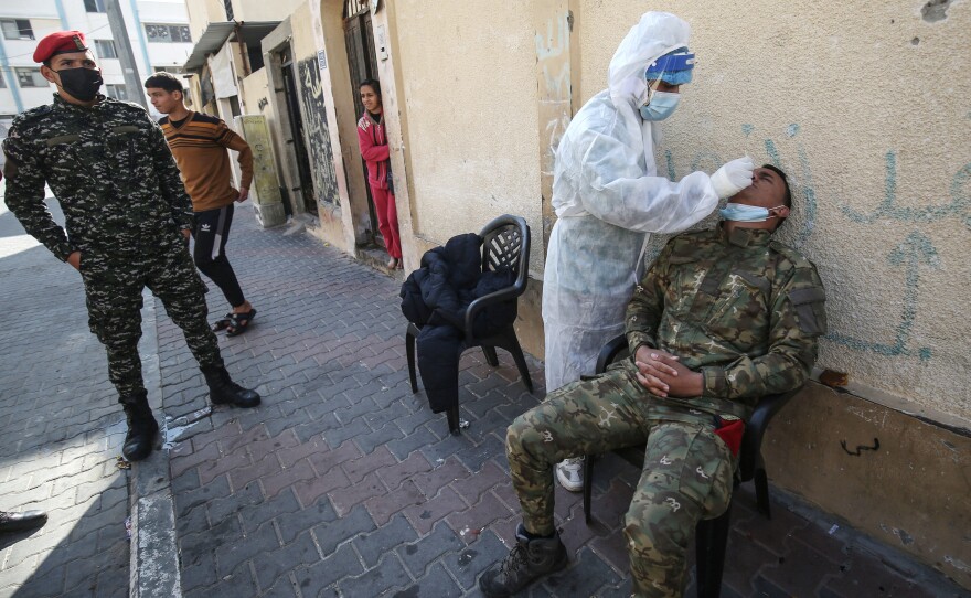 A Palestinian medical worker takes a swab sample from security personnel guarding the homes of quarantined patients infected with the COVID-19 coronavirus in Rafah, in the southern Gaza Strip in January.