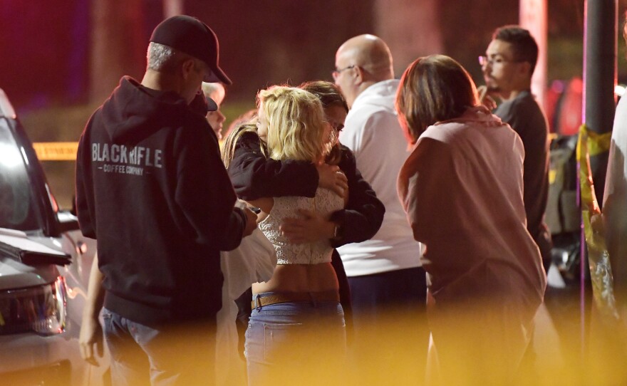 People comfort each other outside a bar in Thousand Oaks, Calif., where a gunman opened fire and killed 12.