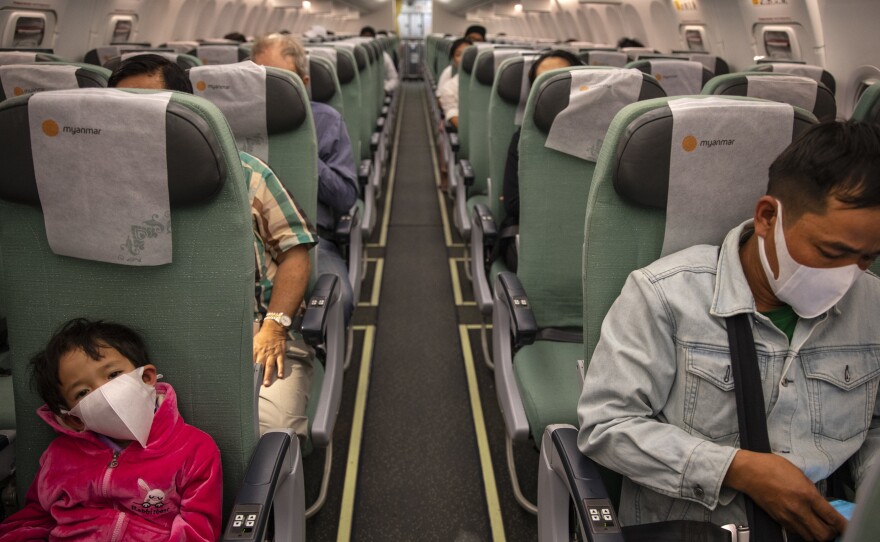 Passengers wear masks on a Myanmar National airlines flight out of Yangon. Many airlines now require passengers to don masks.