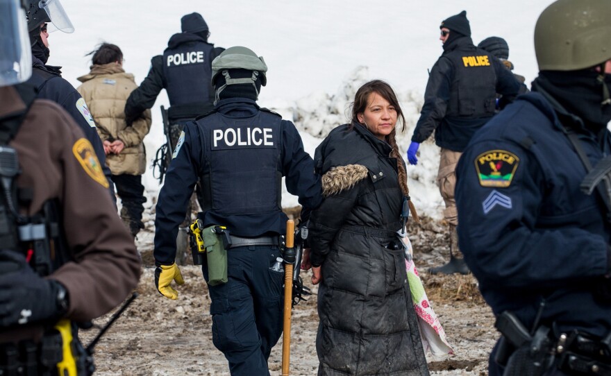 (Top) Police make arrests as they move through the Oceti Sakowin camp. (Bottom) The police moved steadily and slowly through the camp, accompanied by Humvees and maintaining a perimeter of the cleared area.