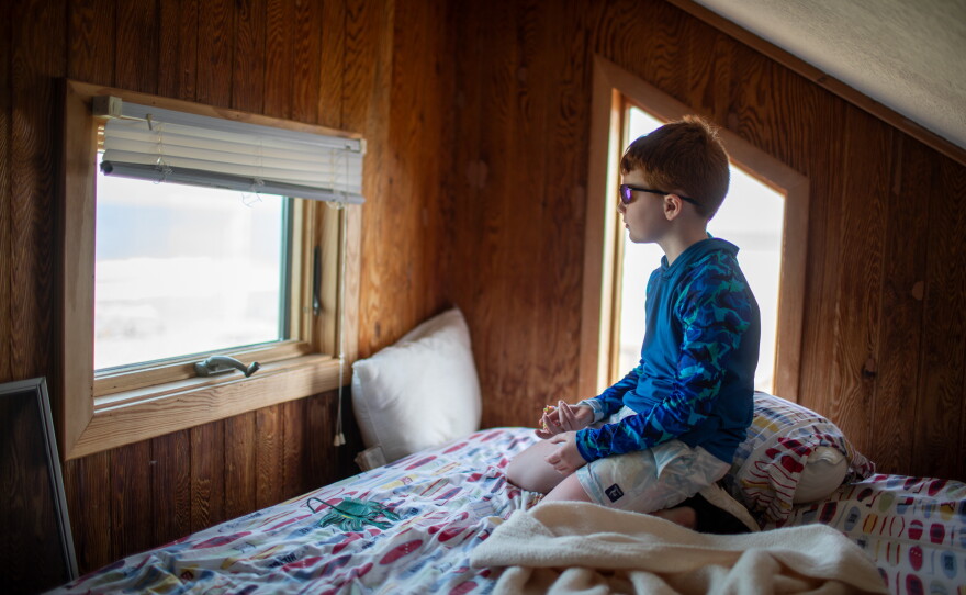 Clarke Lattimore, 8, looks out the window of his family's beach house in Buxton, N.C., in May. His great-grandfather built the house behind two rows of dunes. Now, it is threatened by the ocean.