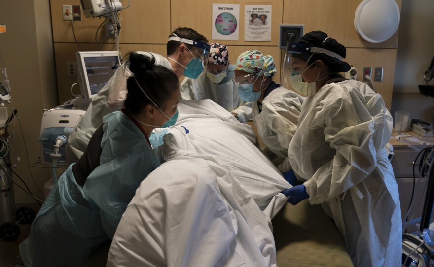 Medical personnel treat a COVID-19 patient at Providence Holy Cross Medical Center in Los Angeles on Thursday. California is imposing an overnight curfew on most residents to blunt a surge in coronavirus infections.