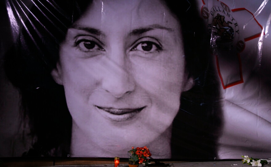 Flowers and a candle lie in front of a portrait of slain investigative journalist Daphne Caruana Galizia during a vigil outside the law courts in Valletta, Malta, Oct. 16, 2018.