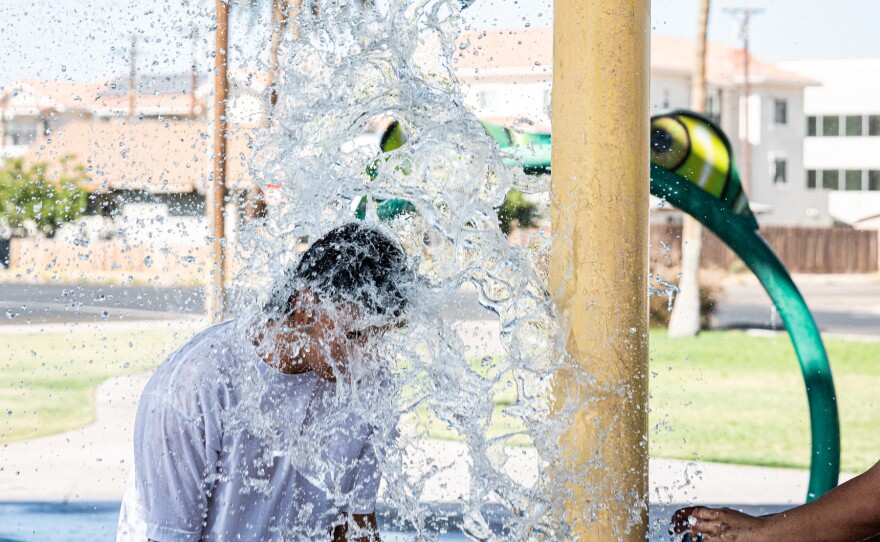 A teen splashes his friend with water in a splash pad in Eager Park, Imperial, Calif. on June 6, 2024.