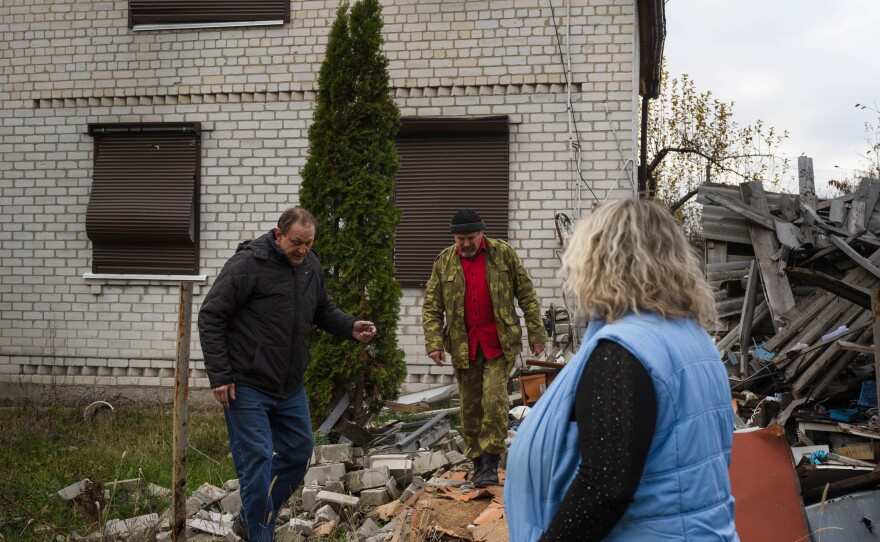 Voinov with Oleksandr Lysytskyi and his wife, Svitalana Maliarova, look at rubble in their neighborhood. They are some of the few residents staying in their village where power is expected to be out for months.