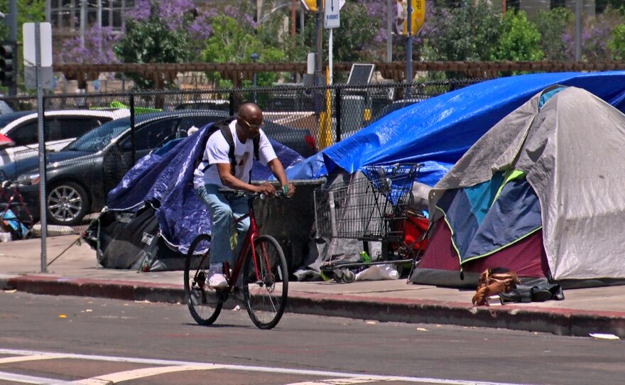 A man riding his bike through a homeless encampment in downtown San Diego, May 31, 2022.