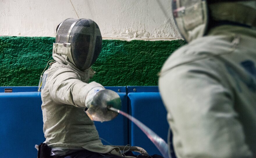 Panos Triantafyllou (left), in his fencing uniform and mask, trains with Vasilis Ntounis, his fellow Paralympic athlete and close friend.