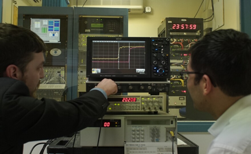 Dr. David Scherer (right) with atomic clock equipment at Microsemi Laboratory.