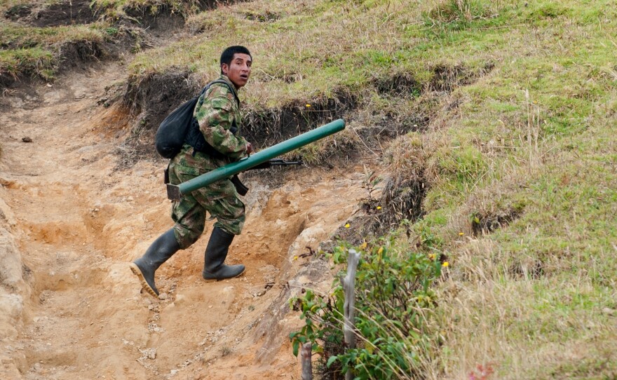 A member of the Revolutionary Armed Forces of Colombia, or FARC, runs to take position during a firefight with the Colombian army in the mountains of Cauca state on July 12. For now, fighting continues even as the two sides prepare for peace talks.