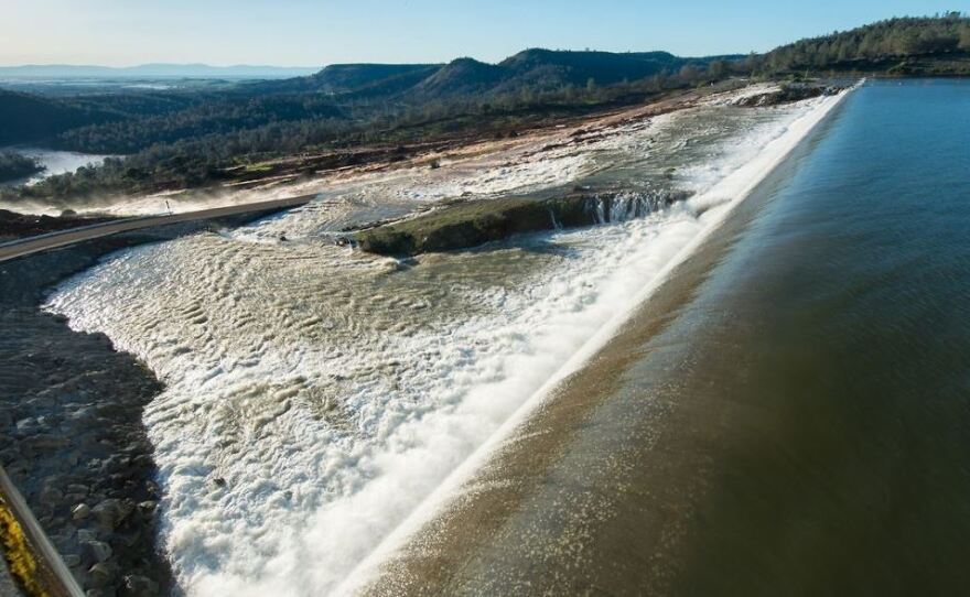 In this scene from Saturday, water is seen flowing over the auxiliary spillway at Oroville Dam, after the lake level exceeded 901 feet above sea level. The water carved a path to the Feather River, in the distance.
