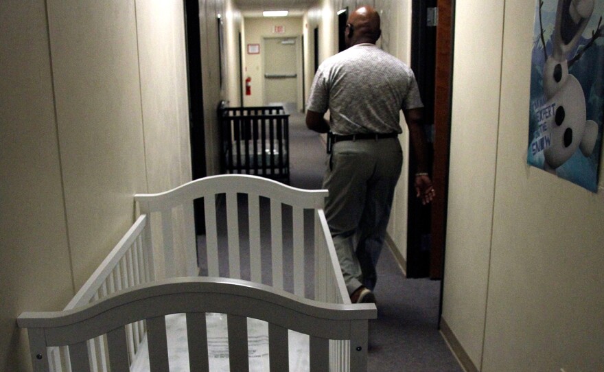 A federal employee walks past cribs inside the family detention center in Artesia, N.M., in June.