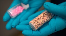A forensic chemist with the Drug Enforcement Administration holds vials of fentanyl pills at a DEA research laboratory in this file photo. Fentanyl deaths are plunging in the U.S, but the recovery is threatened by a new "synthetic soup" of toxic street drugs.