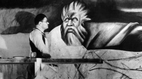 Black and white photo of Mexican muralist José Clemente Orozco at work painting. 