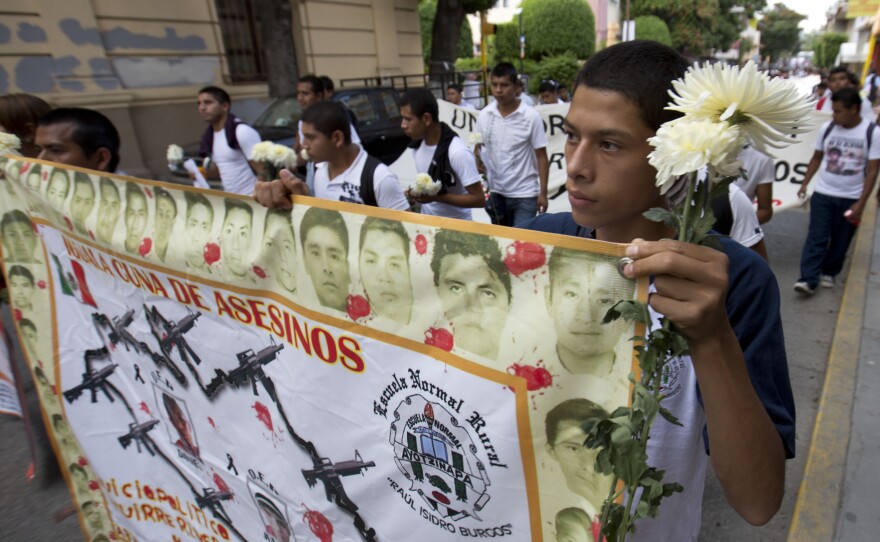 Students hold a banner with the faces of the missing that reads in Spanish "Iguala, cradle of murders."