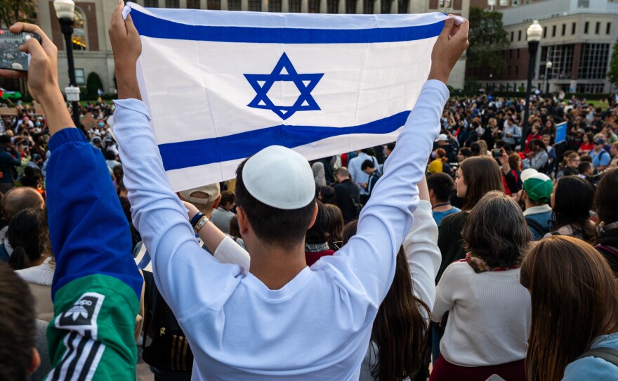 A man holds up an Israeli flag overlooking a pro-Gaza rally at Columbia University on Thursday.