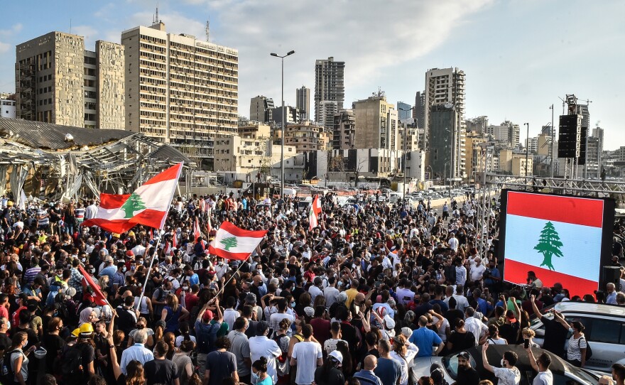 People wave Lebanese flags at a protest near the Beirut port on Tuesday. Last week's explosion is seen by many Lebanese as a deadly manifestation of government malpractice.