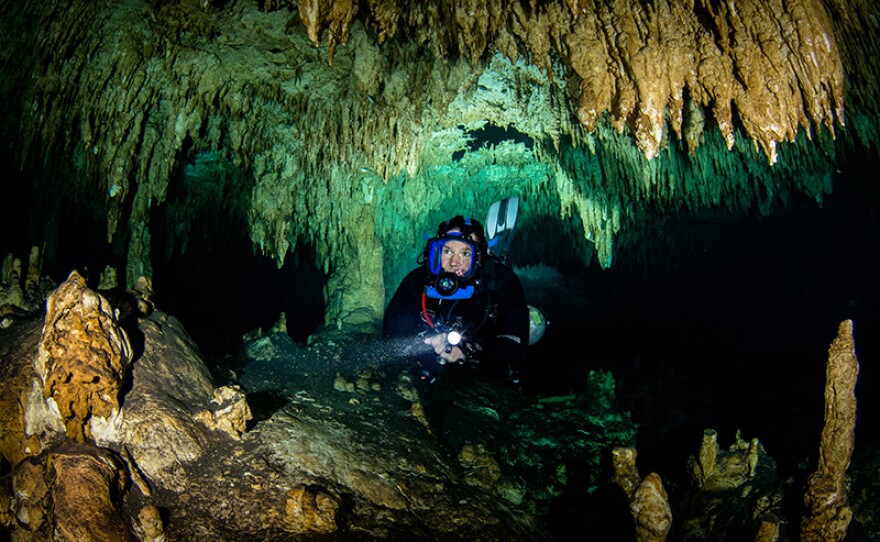 Steve swimming through Cenote in diving gear. Mexico. 