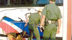 Border Patrol agents inspect the cargo area of a bus.