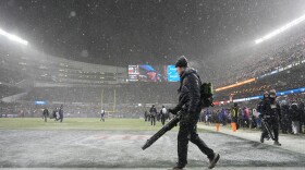 Grounds crew members glow snow off the field at Soldier Field during the first half of an NFL football divisional playoff game between the Chicago Bears and the Los Angeles Rams Sunday, Jan. 18, 2026, in Chicago.