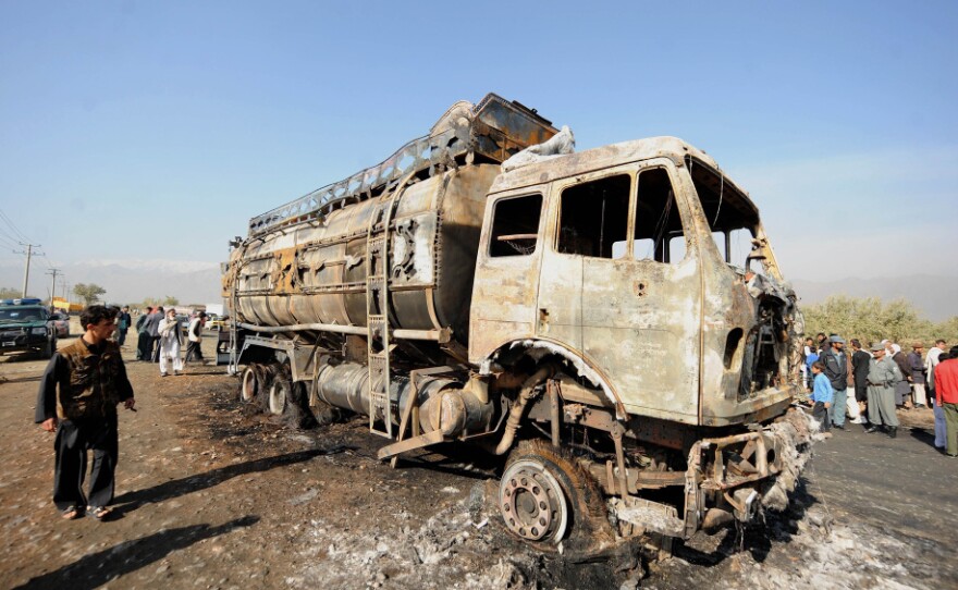 Afghan policemen and locals watch a burned-out fuel truck, supplying a U.S.-run base, after being targeted by a bomb near Bagram Air Field near Kabul on Oct. 26. Attacks on convoys carrying supplies to U.S. troops are costly — both in monetary terms and in human life.
