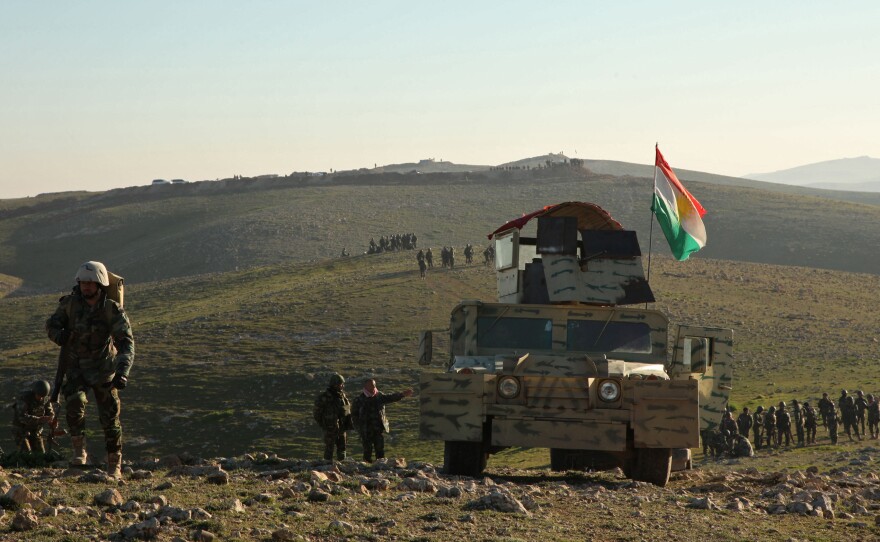 Kurdish peshmerga fighters walk with their weapons as they take control of the area, on the outskirts of Mosul on Feb. 6.