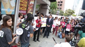 Wendy's employee Debra Flores looks behind her at her place of employment while addressing the crowd at a rally calling for higher wages, Aug. 29, 2013. 