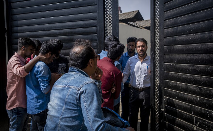 Students from the National Institute of Technology Srinagar talk to a security guard as they wait to enter the newly opened multiplex in Srinagar on Oct 1.