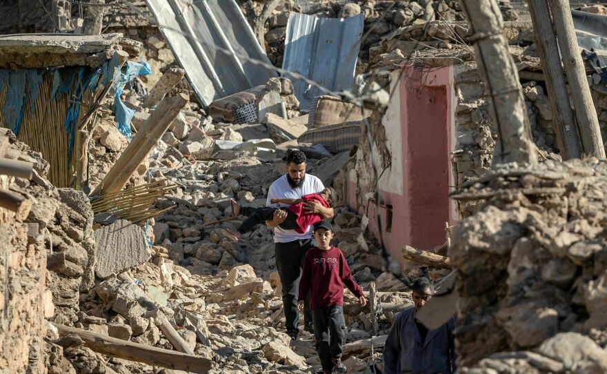 People walk past destroyed houses after an earthquake in the mountain village of Tafeghaghte, southwest of the city of Marrakech, on Saturday.