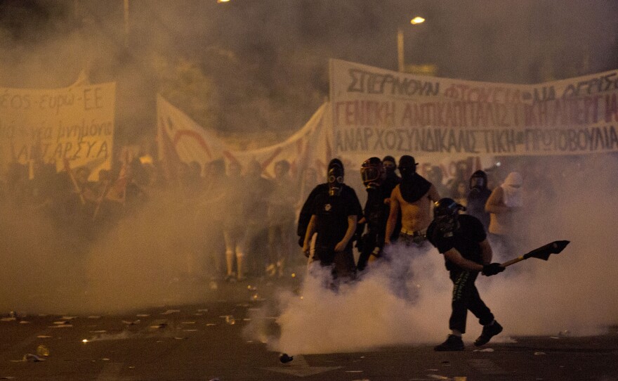 An anti-austerity protester pushes away a tear gas canister thrown by riot police during clashes in Athens on Wednesday.