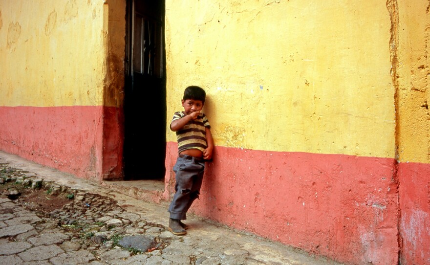 A child in Guatemala leans against a colorfully painted wall, Jan. 3, 2010.