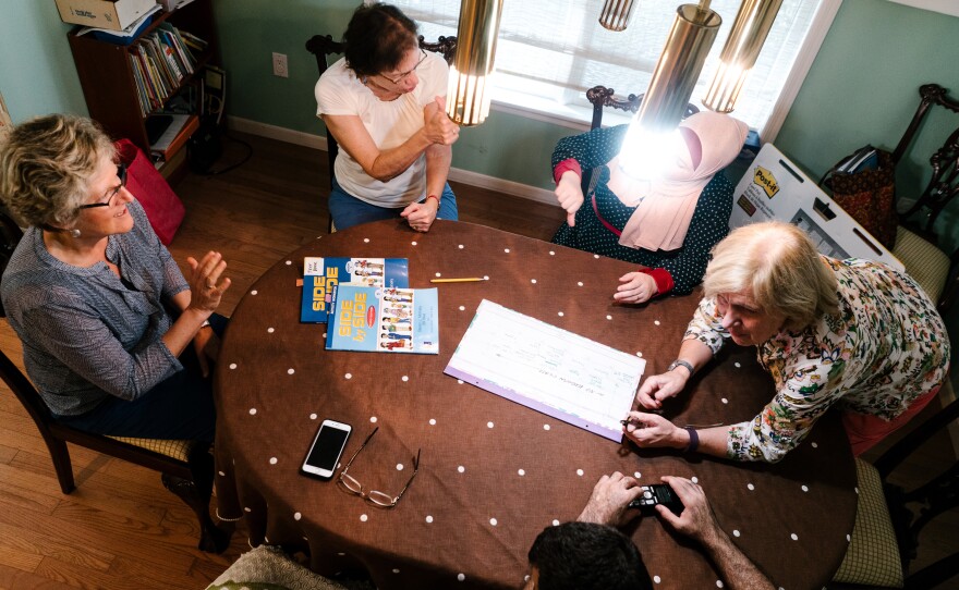Beverly Leach (right) leads an ESL course for Ghada and her husband Osama, two newly resettled refugees from Syria, in their home. They are accompanied by other volunteers.