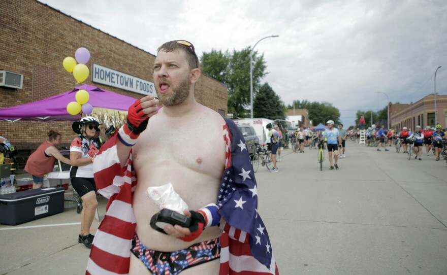 Brett Griffin of Oswego, Ill., eats popcorn as he walks down the streets of Schaller, Iowa, wearing an American flag and star-spangled speedo Tuesday, July 25. Griffin, who said this is his seventh time on the ride, said he and other members of his team, Giraffe's Up In The Air, wear the eye-catching costumes to draw attention to their fundraising efforts for children's cancer research.