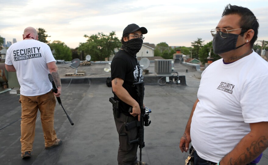 Armed volunteers take up rooftop positions in a Minneapolis neighborhood; those who are not allowed to carry guns are kept off the roof.